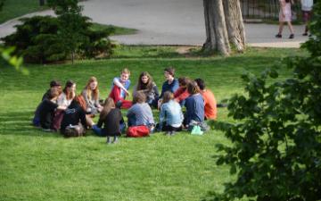 Students sit in circle on a grass lawn 