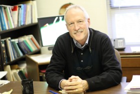 A man smiling at his desk in an office.