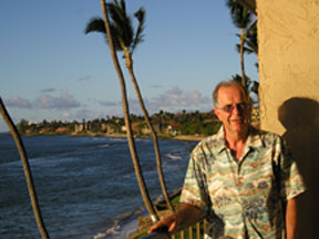A person standing outdoors with ocean in the background.