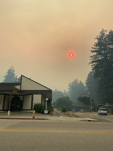 A building surrounded by smoky haze and an eerie, reddish sun.