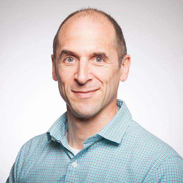 A person wearing a light blue shirt against a plain background.
