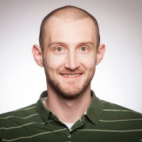 A person smiling, wearing a green striped shirt.