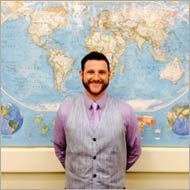 A person smiling in front of a world map.