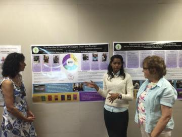 Three people standing in front of the Resilient Families poster display.