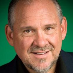 Larry Brilliant smiling against a green background.