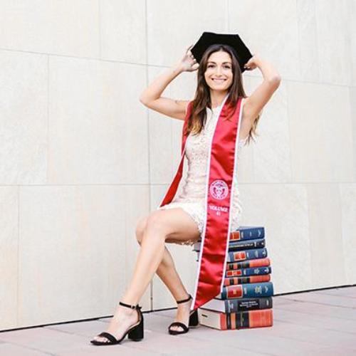 Elia Kazemi in graduation attire in front of Hall of Law sign
