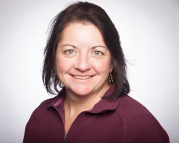 A person smiling, wearing a maroon shirt.