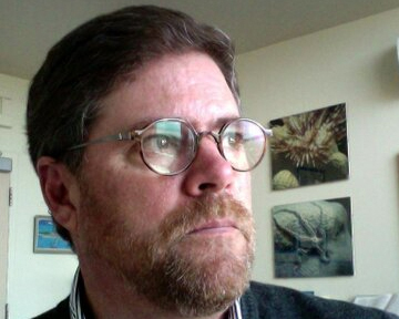 A person wearing glasses, looking off-camera.