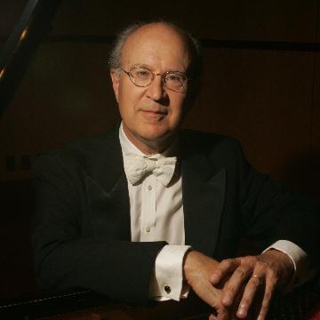Man in formal attire sitting at a piano.