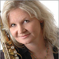 A person holds a saxophone, smiling.