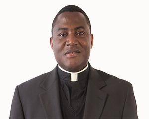 A man wearing clerical attire and a suit jacket.