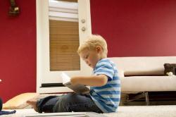 A child in a striped shirt sitting on a bed.