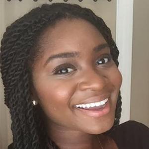 Smiling woman with braids wearing a black top.