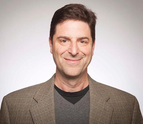 A man wearing a blazer, smiling at the camera.