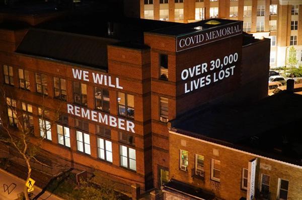 Building with 'Covid Memorial' message lit up at night.