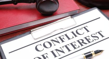 A desktop with book, gavel, clipboard, and pen, and document that has the words, Conflict of Interest.