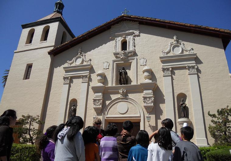 California History docent speaking to a school group outside Mission Santa Clara.