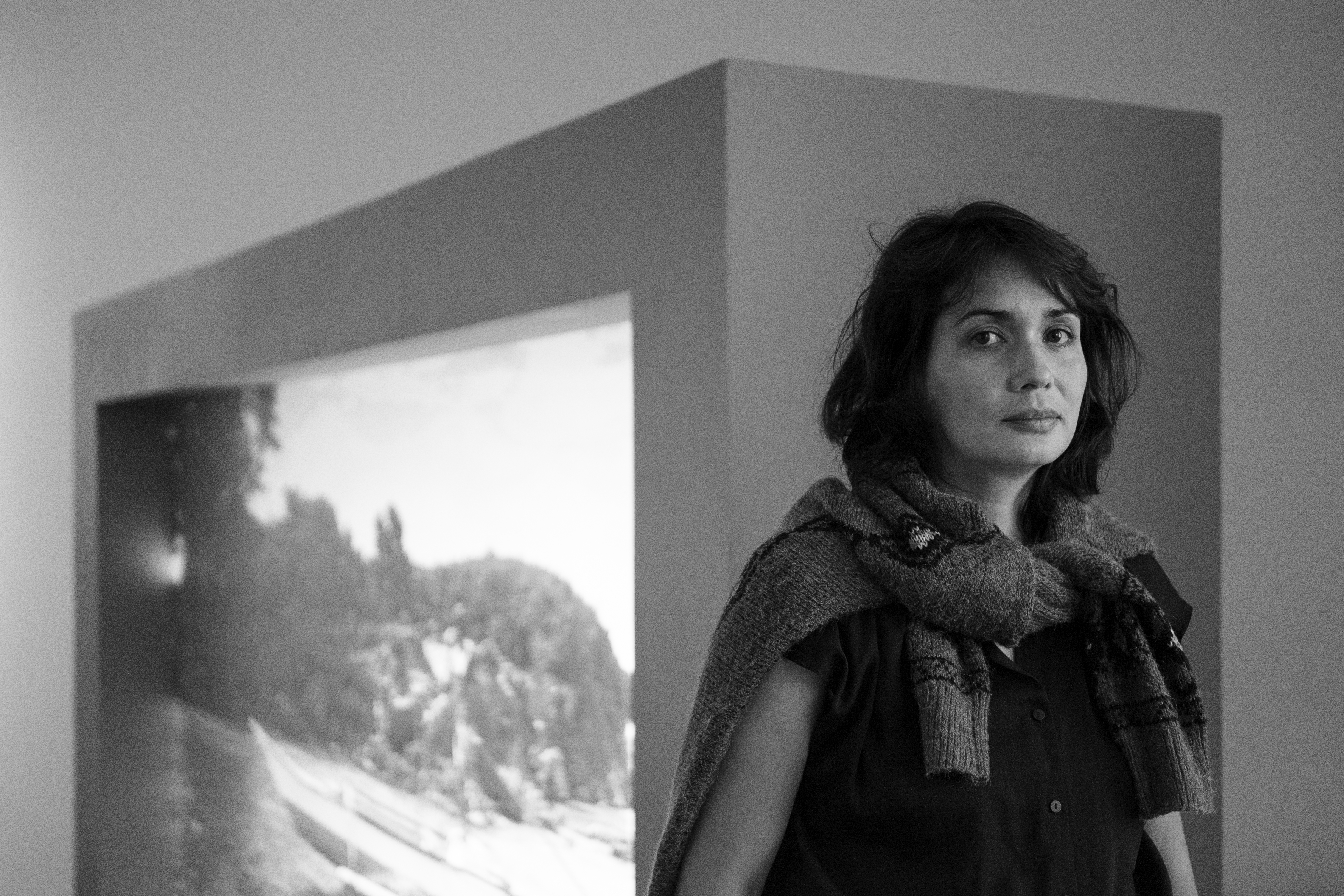 Black and white photograph of woman with dark hair and projected image in background
