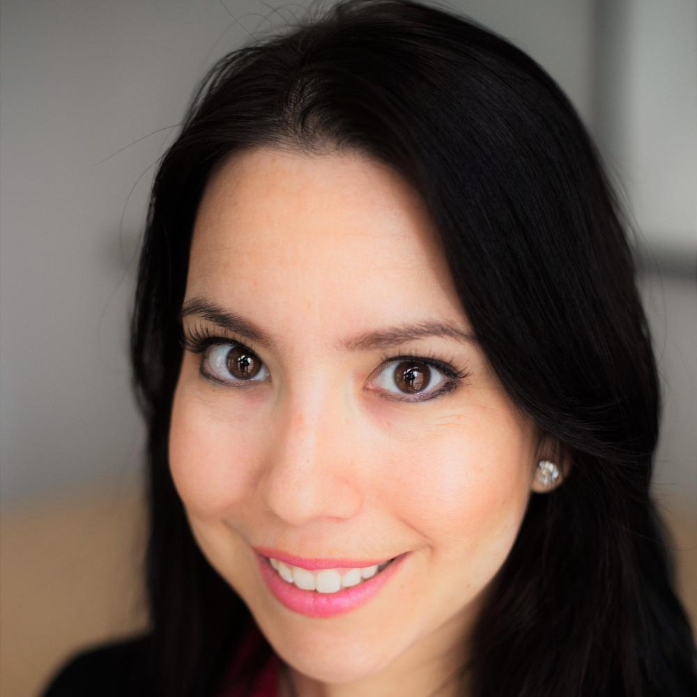 Smiling woman in professional attire with neutral background.