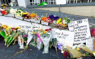 Flowers and handwritten signs laid on pavement in memory of a person.