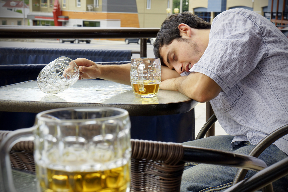 Young man passed out with beer in hand.