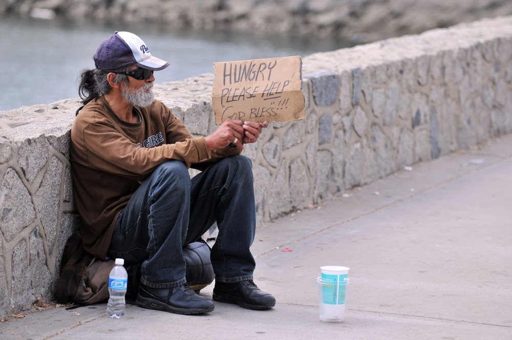 Homeless man holding sign that says Hungry, please help. God bless!
