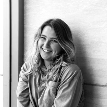 A person leaning against a wall and smiling.