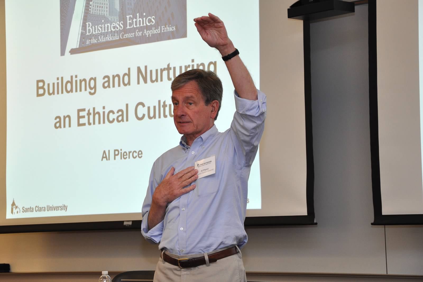 A person speaking in front of a presentation on Building Charismatic and Ethical Cultures.