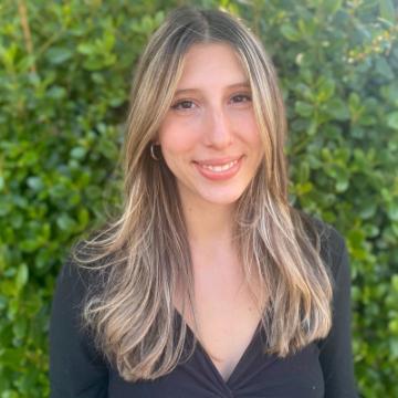 A person smiling in front of green foliage.