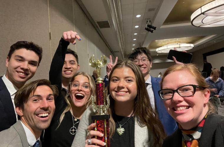 Fourth-place-winning 2022-23 Ethics Bowl team and advisor Dr. Erin Bradfield with their trophy.
