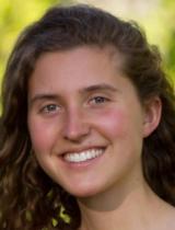 A person smiling with a greenery background. image link to story