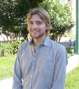 A person smiling outdoors in front of trees and grass. image link to story