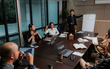 group of people sitting around a table watching a presenter