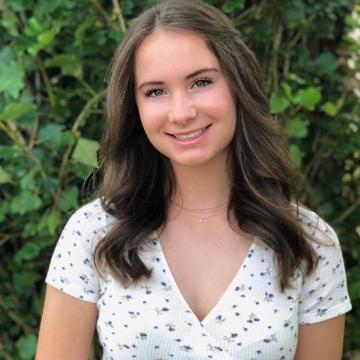 A person smiling in front of green foliage.
