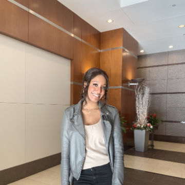 A person standing in a professional lobby, smiling.