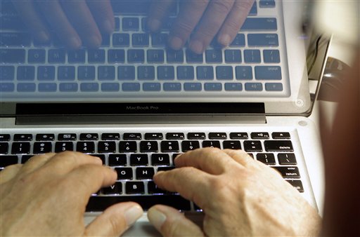 Hands typing on a laptop with code on the screen.