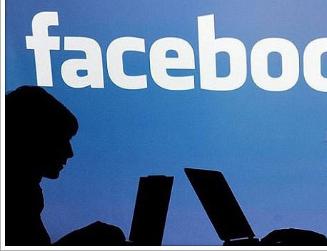 silhouettes in front of Facebook partial sign