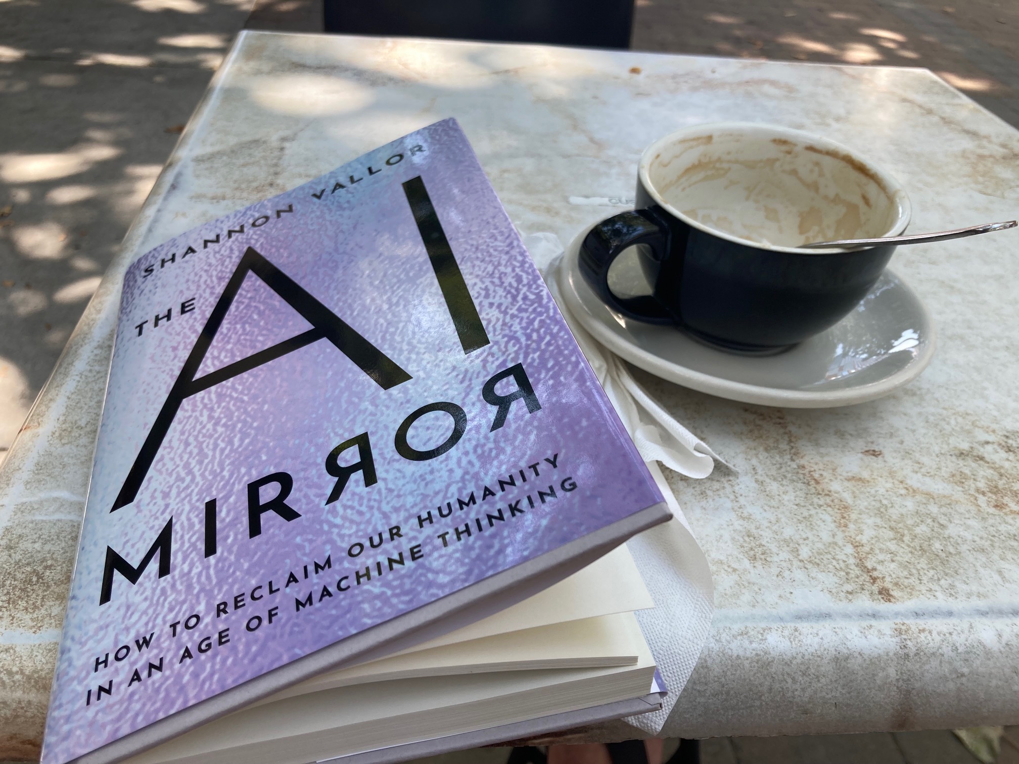 book and coffee cup on a saucer on a table