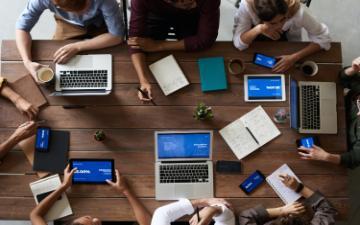Top view of people around a table using technology devices 