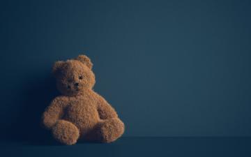 A teddy bear against a dark blue background.