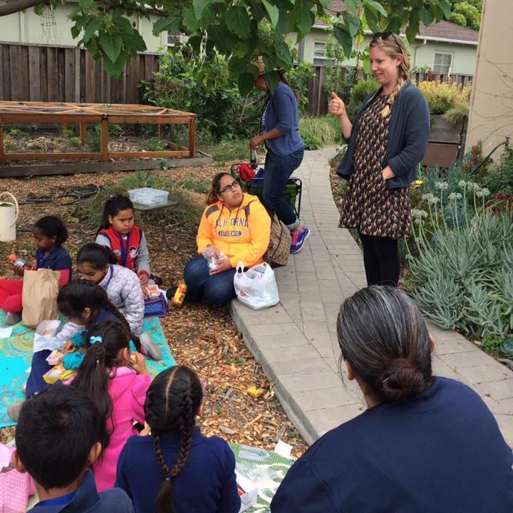 A group sitting outdoors, one person standing and talking.