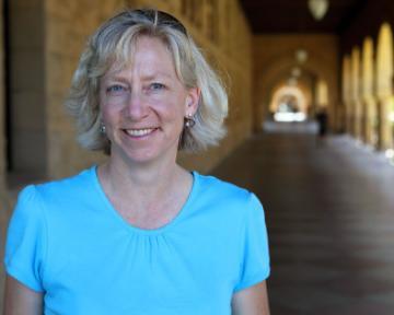 A person in a blue shirt smiling in a corridor.
