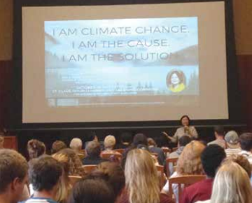 Presentation in lecture hall with speaker in front of projected screen.