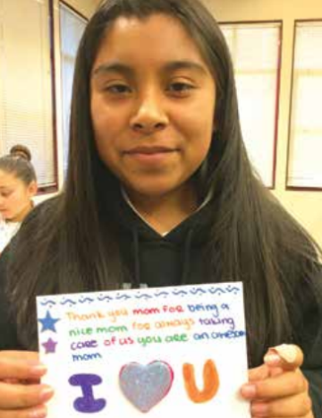 A person holding a colorful, handwritten note with I ?? U at the bottom.