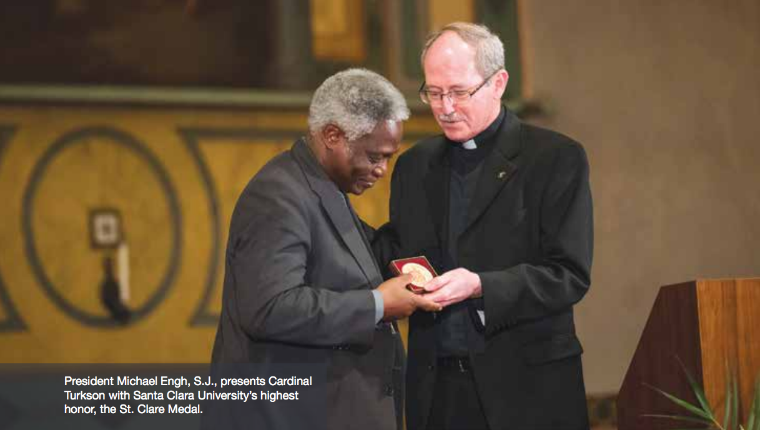 Two clergymen exchanging a red item inside a traditional building.