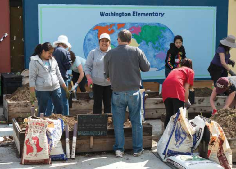 People working together in front of a mural with the text World Peace.