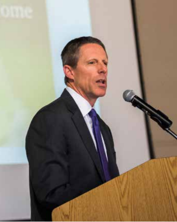 A person speaking into a microphone at a lectern.