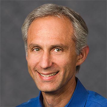 A smiling individual with a grey background.