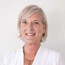 A woman wearing a white shirt, smiling against a plain background.