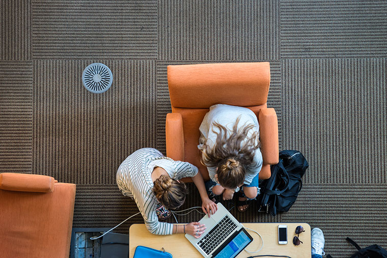 Two people read books at a library, viewed from above.